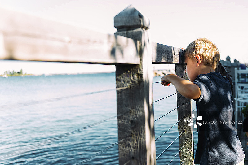 男孩透过木栅栏看五大湖的侧视图图片素材
