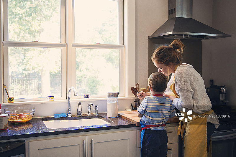 母亲和儿子在厨房做饭的后视图图片素材