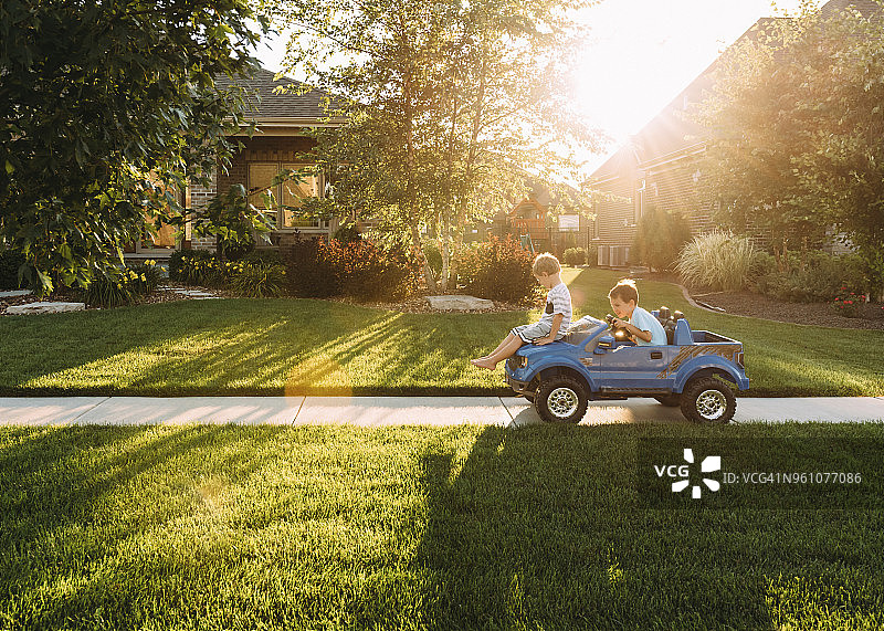 兄妹或姐弟在院子里的人行道上玩玩具车图片素材