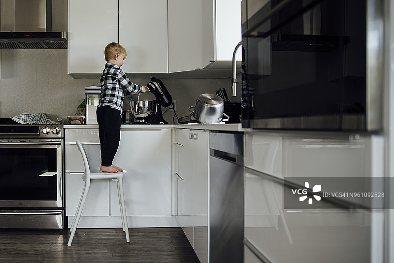 男孩在厨房使用电动搅拌器的全身照图片素材