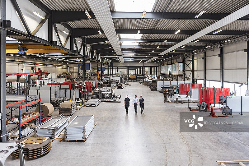 三名男子在工厂车间行走交谈图片素材