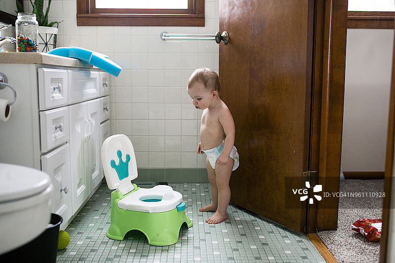 半裸女婴看着浴室里的便盆图片素材