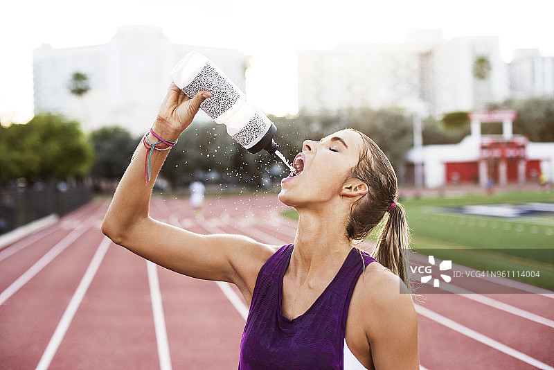 在赛道上喝水的女运动员图片素材