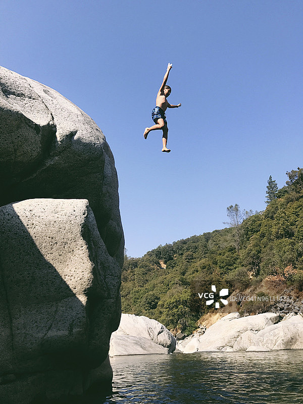 仰视：无忧无虑的无上衣男孩从悬崖跳入尤巴河图片素材