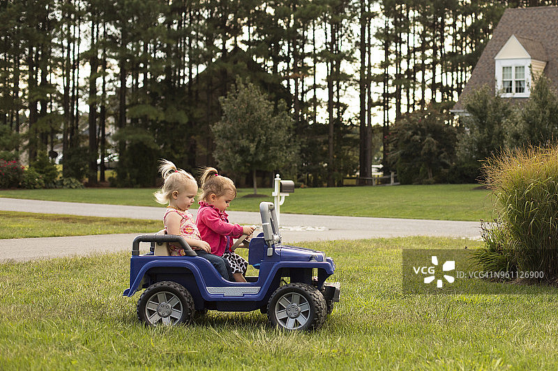 姐妹俩在后院草地上玩玩具车图片素材