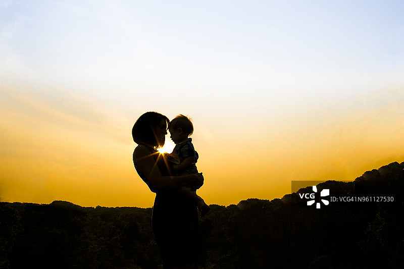 日落时分，母亲在公园里抱着儿子的轮廓图片素材