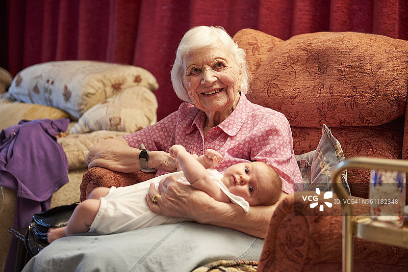年长的女人在扶手椅上抱着曾孙女，肖像照图片素材
