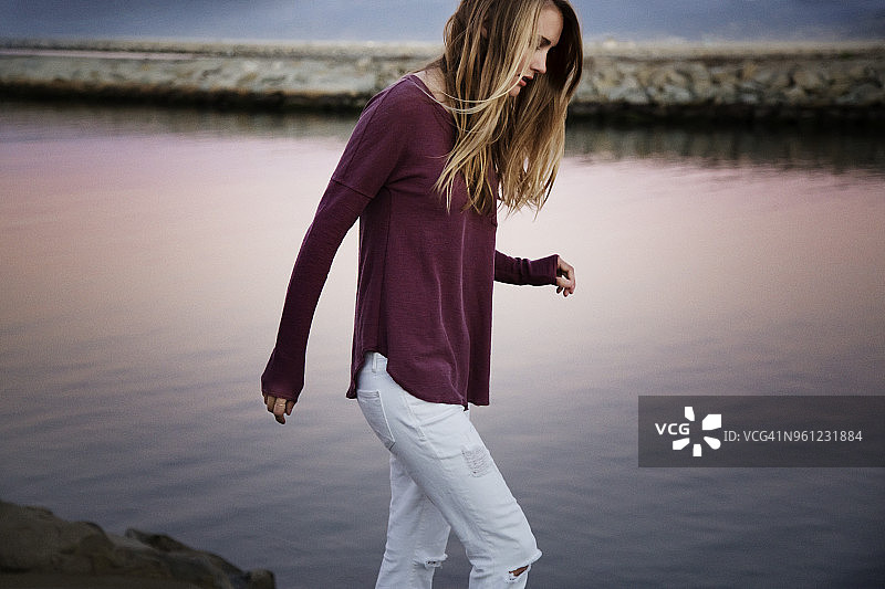 日落时分，女子在湖边漫步侧视图图片素材
