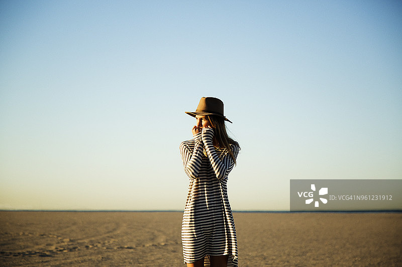 站在海滩上，背景是晴朗蓝天的沉思女人图片素材