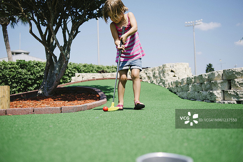 阳光明媚的日子里，女孩在玩迷你高尔夫图片素材