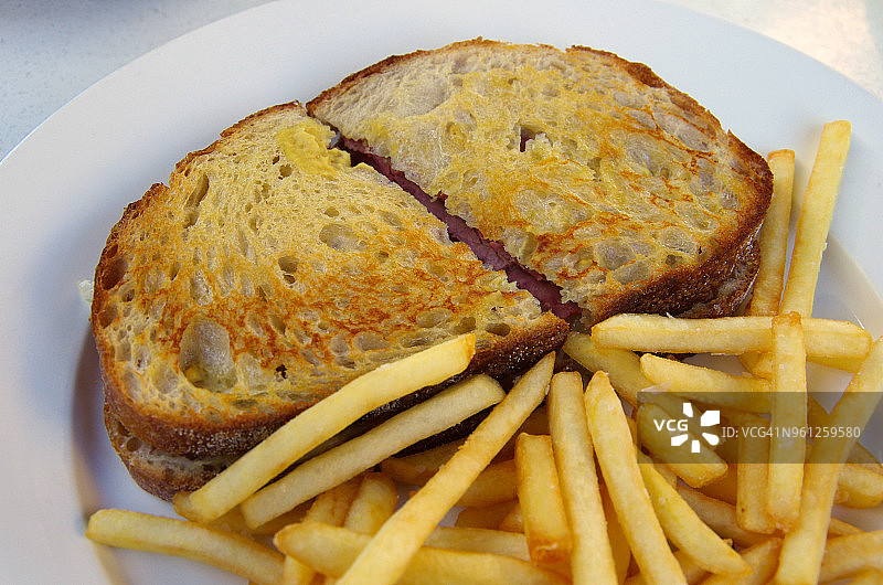 烤鲁本三明治（腌牛肉、德国泡菜、瑞士奶酪和千岛酱）配薯条图片素材