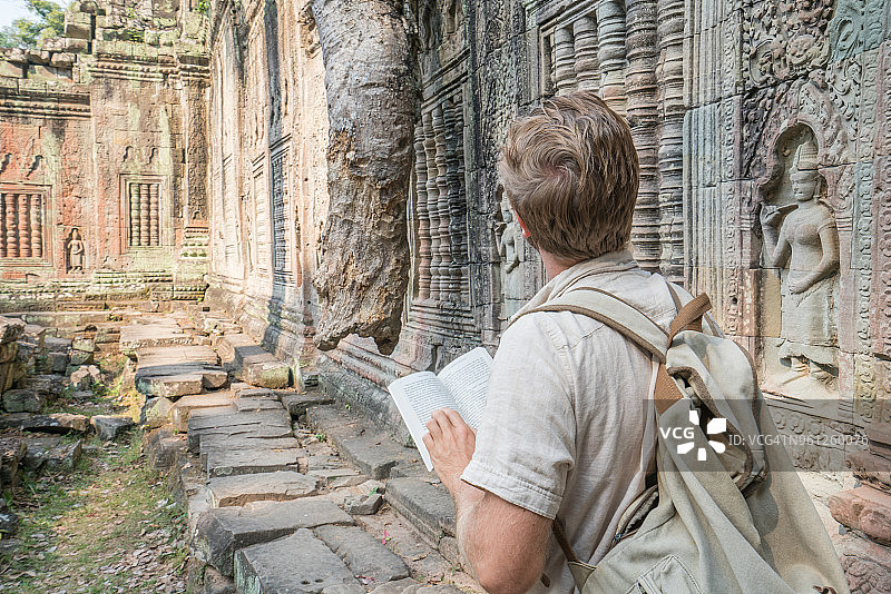 在柬埔寨古庙阅读旅游指南的年轻男子图片素材