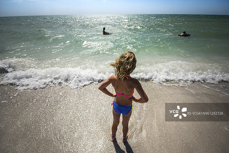 双手叉腰站在海滩上的女孩的高角度视图图片素材