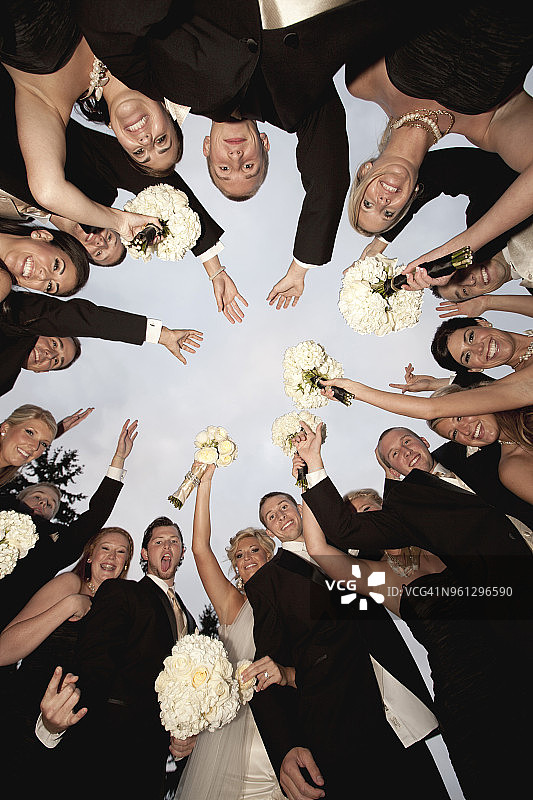 快乐的朋友们与新娘新郎举起手臂的仰视图图片素材