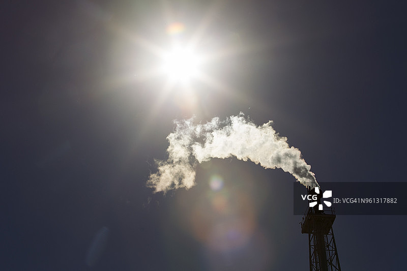 晴天，炼油厂烟囱冒出的烟仰视图片素材