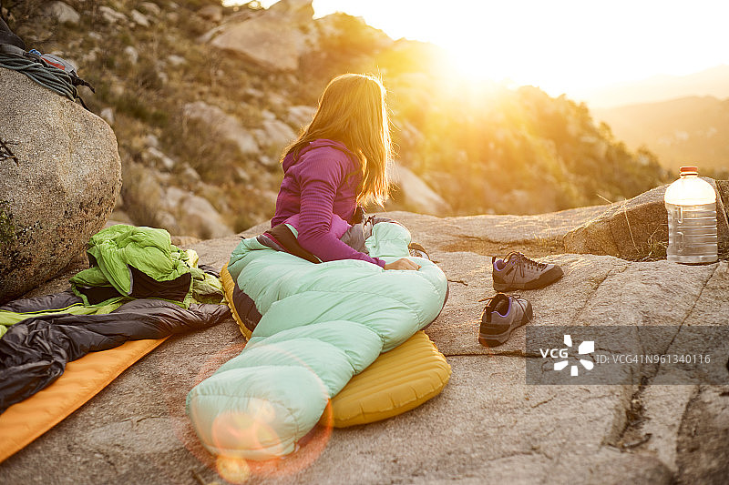 在岩石上放松时看向远方的睡袋女人图片素材