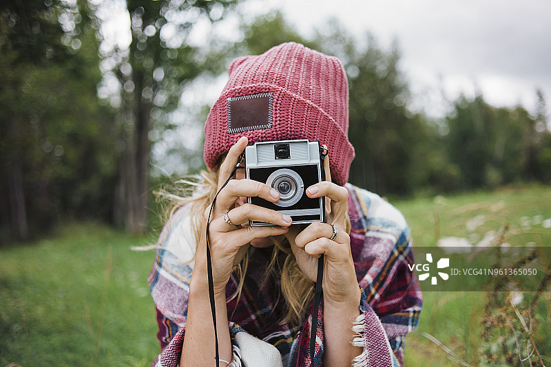 女人在草地上用一次成像相机拍摄图片素材