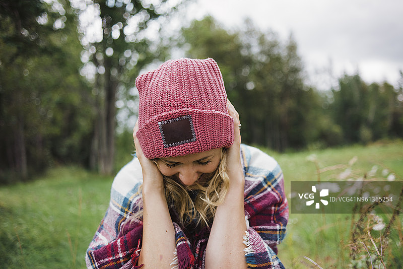 心情愉悦的女人站在田野上调整针织帽图片素材