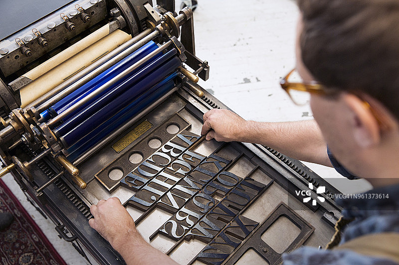 俯视角度拍摄的男人在机器上整理木制字母图片素材