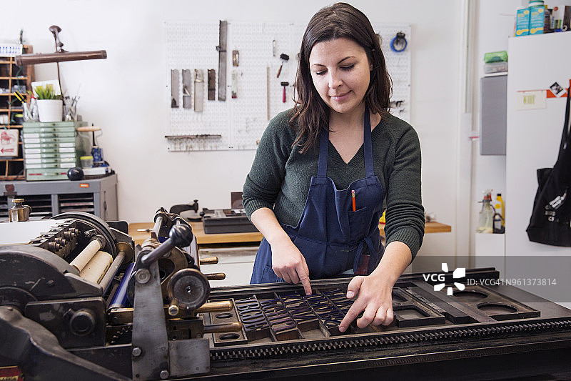 在印刷机上排列字母的女人图片素材