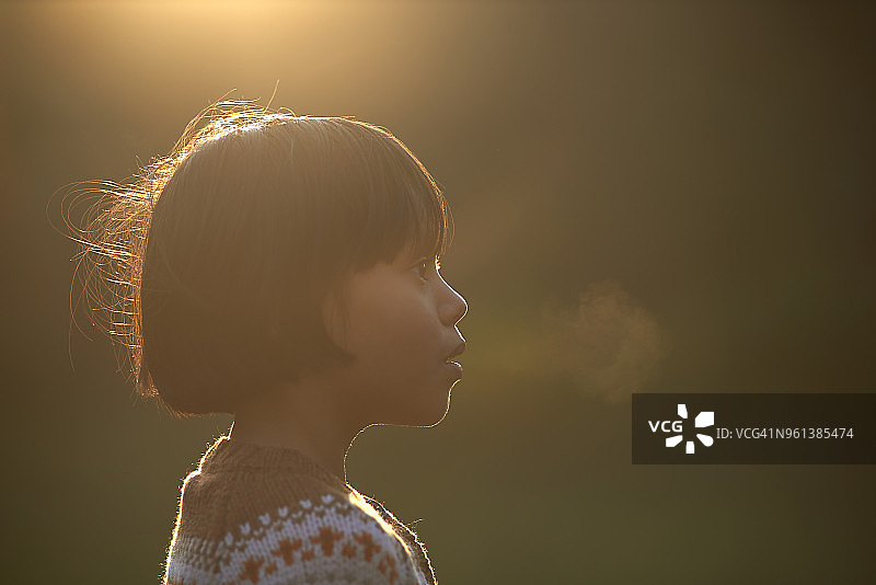 冬日阳光下，女孩呼出雾气的特写图片素材