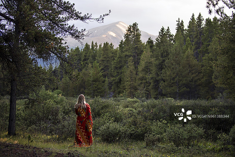 裹着毯子站在森林中的女子背影图片素材