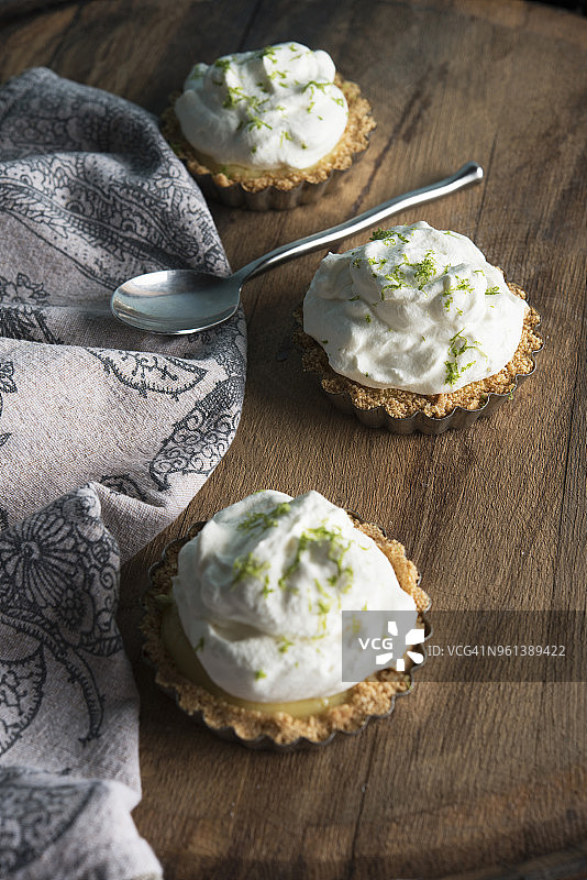 木桌上的酸橙馅饼与勺子、餐巾高角度视图图片素材