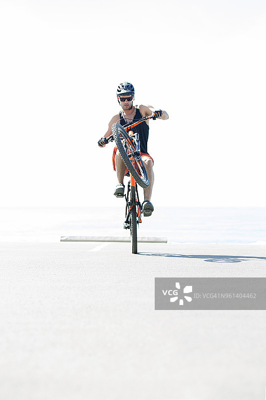 阳光明媚，男人骑自行车表演特技图片素材