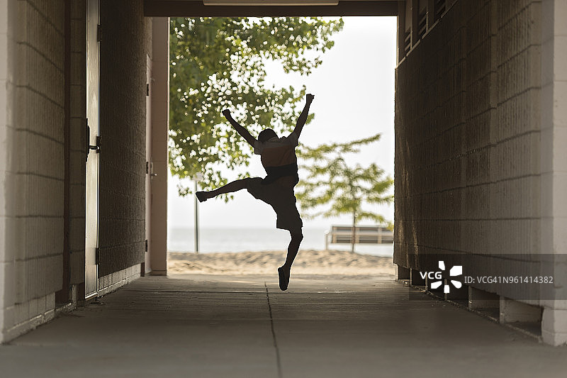 兴奋的男孩在有遮盖的走道上跳跃图片素材