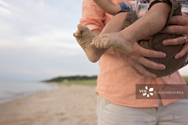 父亲在海滩上抱着儿子玩耍的半身像图片素材