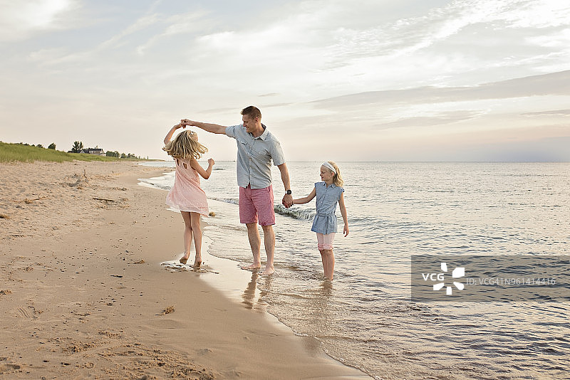 父亲在海滩上和女儿们玩耍图片素材