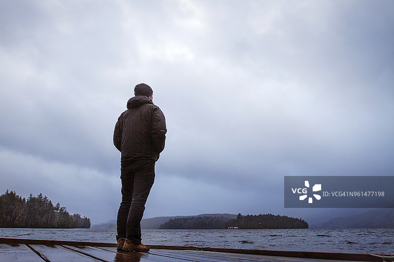 男人站在码头上，在阴天里看着河流图片素材