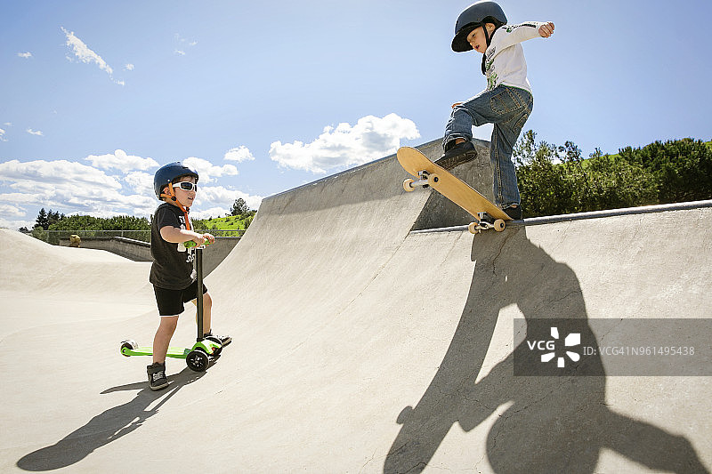 男孩看着朋友在滑板坡道上表演特技图片素材