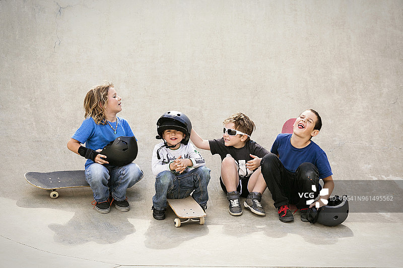 快乐的男孩坐在滑板坡道上聊天图片素材