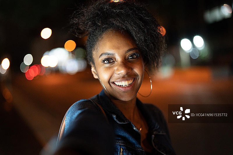 迷人的年轻非洲裔女子夜晚牵着男友的手在城市里散步图片素材
