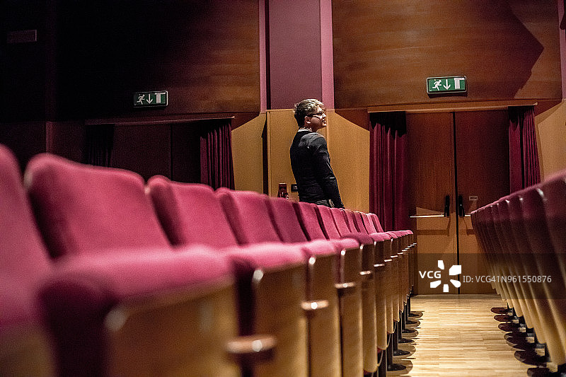 在剧院里站起来的年轻男人图片素材