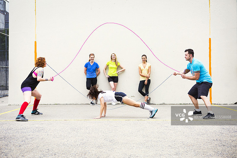 在人行道上靠墙享受跳绳乐趣的快乐女人们图片素材