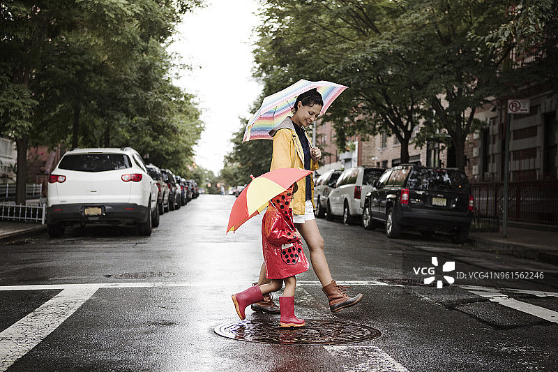 母亲和女儿撑着伞过马路的侧视图图片素材