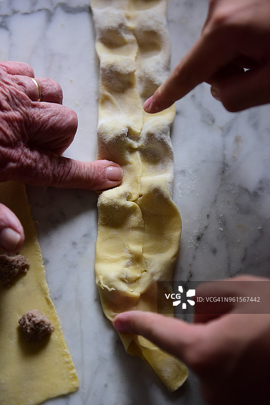 按压新鲜的意大利面皮制作意大利饺子图片素材
