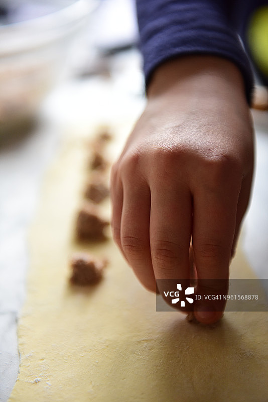 在新鲜的意大利面皮上依次加入少量馅料，制作 tortellini图片素材
