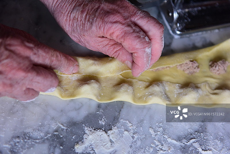 按压新鲜的意大利面皮制作意大利饺子图片素材
