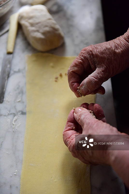 在新鲜的意大利面皮上依次加入少量馅料，制作 tortellini图片素材