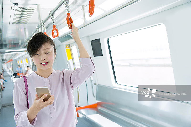 女人在地铁车厢里使用手机图片素材