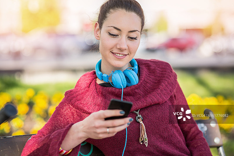 坐在公园长椅上发短信的女人图片素材