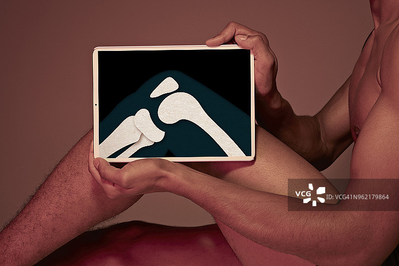 年轻男人手持平板展示膝盖骨图片素材