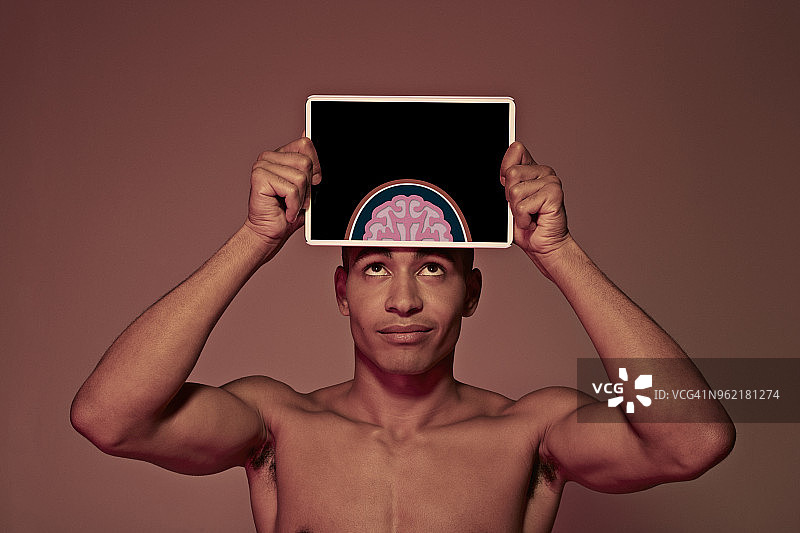 年轻男人把平板电脑放在头前展示大脑图片素材