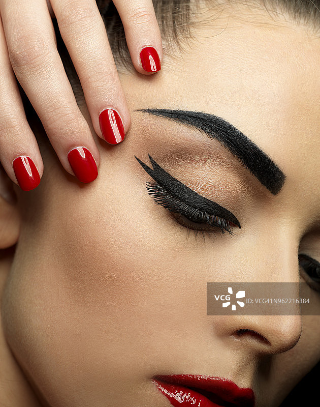 涂红色口红、红色指甲油和黑色眼线的女人特写图片素材