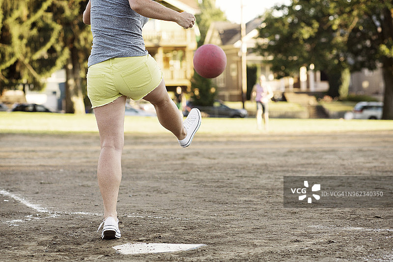 女子在棒球场上踢躲避球图片素材