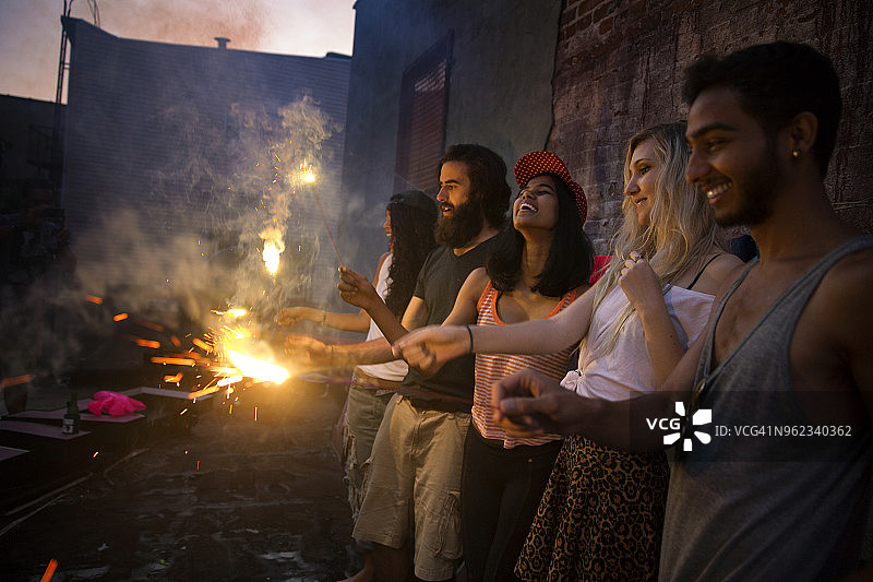 朋友们在花园派对日落时分玩烟花棒图片素材