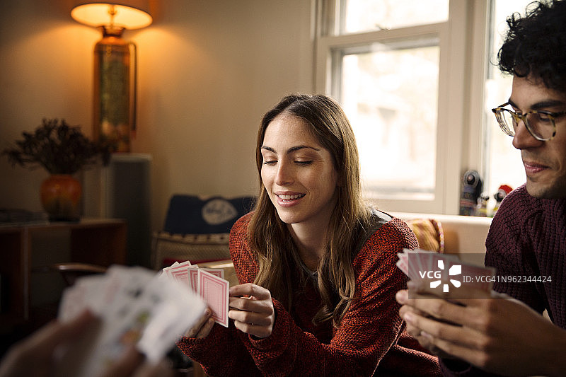 在家休息时玩纸牌的快乐朋友们图片素材
